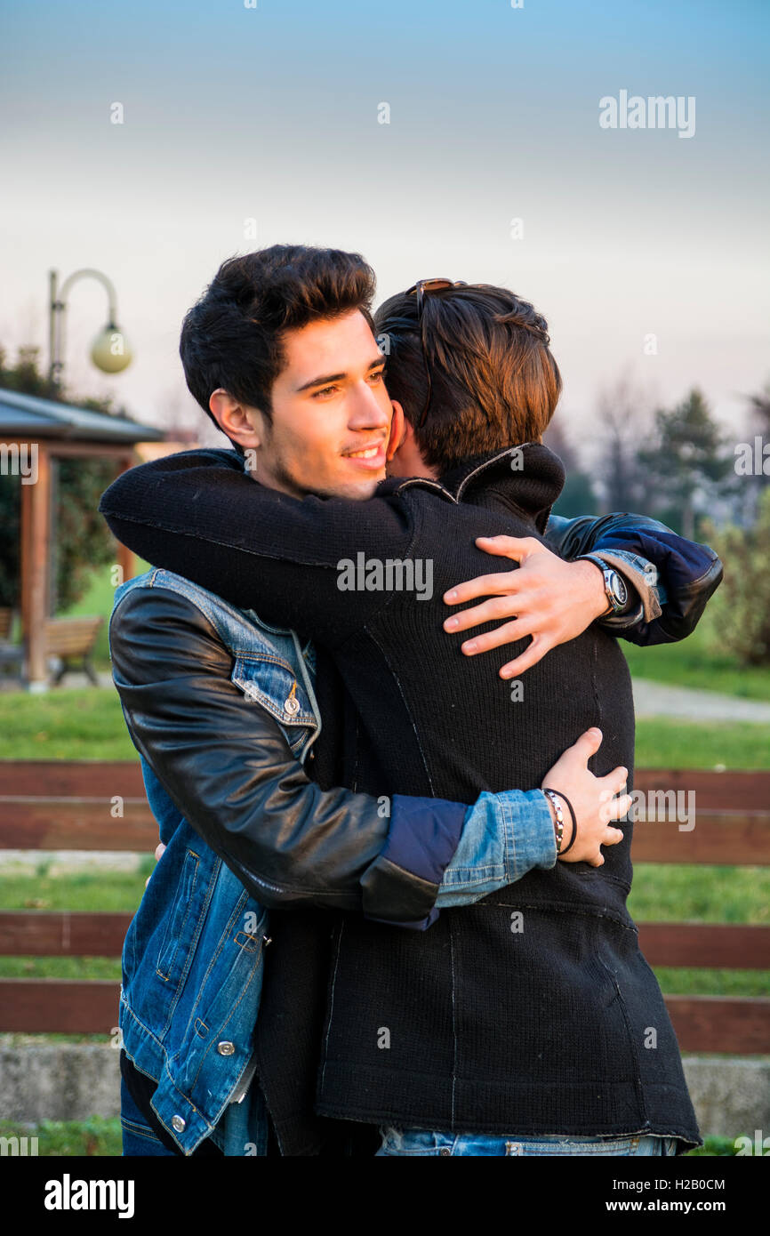 Portrait of cheerful and handsome man hugging his best friend and ...