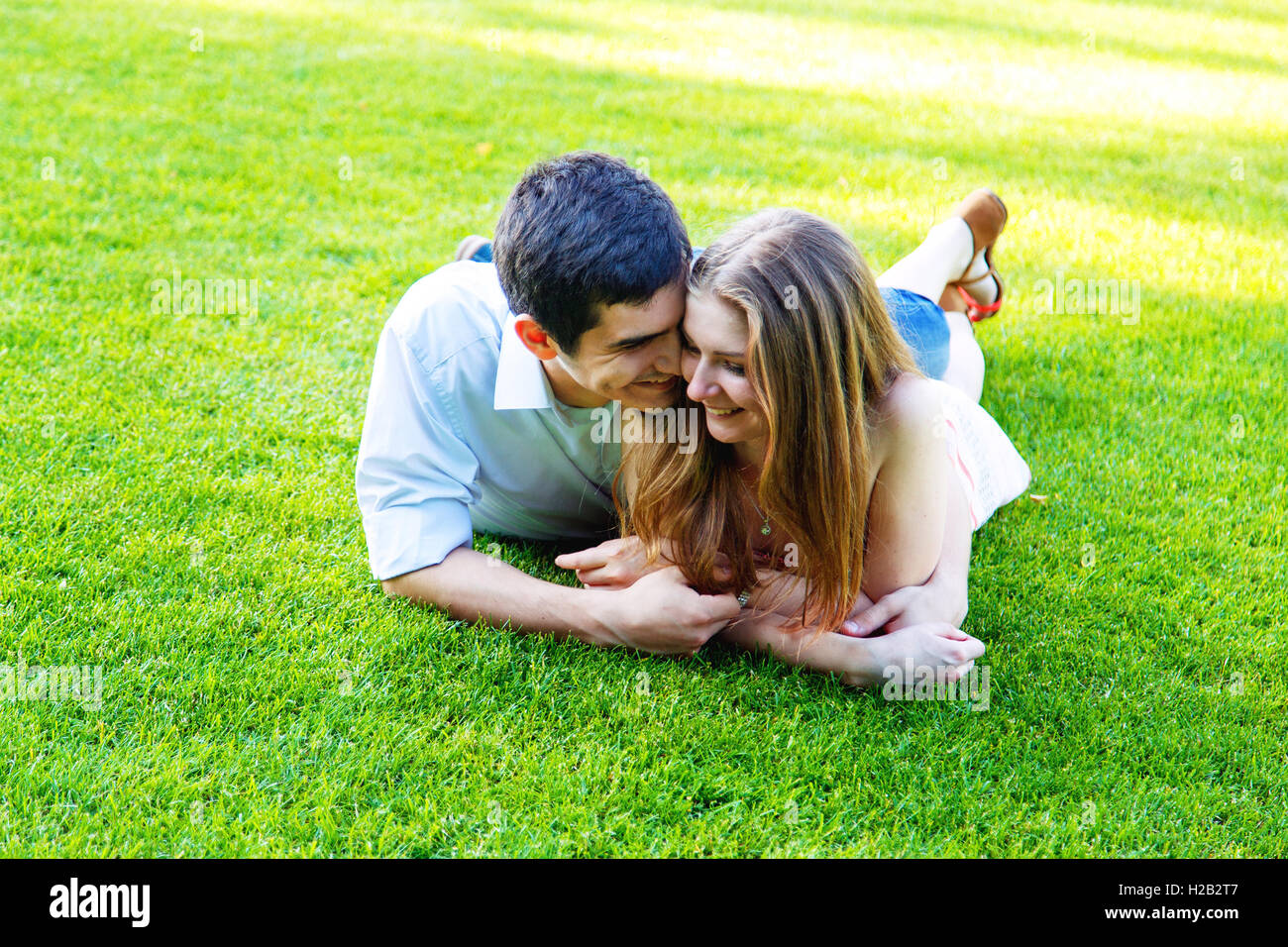 Couple lying on green grass in the park Stock Photo - Alamy