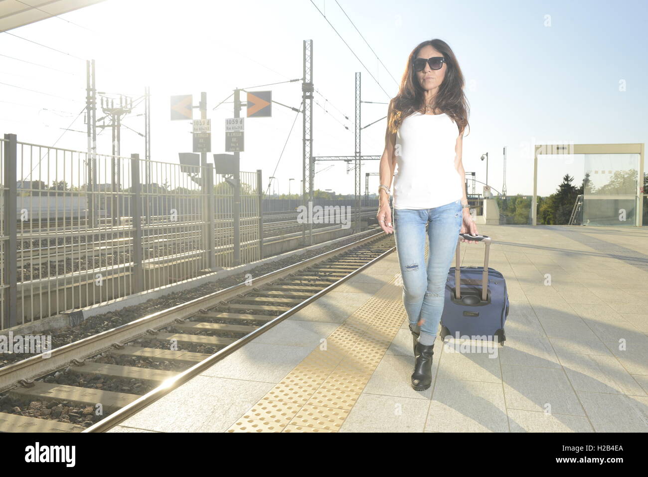 Woman with suitcase - baggage - trolley - in train station Stock Photo