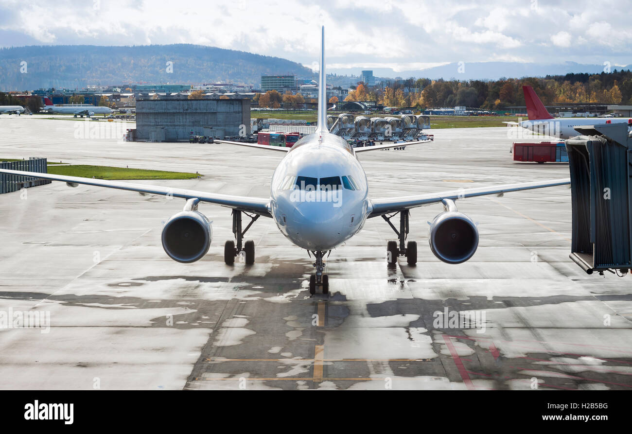 Airplane arriving at the airport terminal with cloudy sky Stock Photo