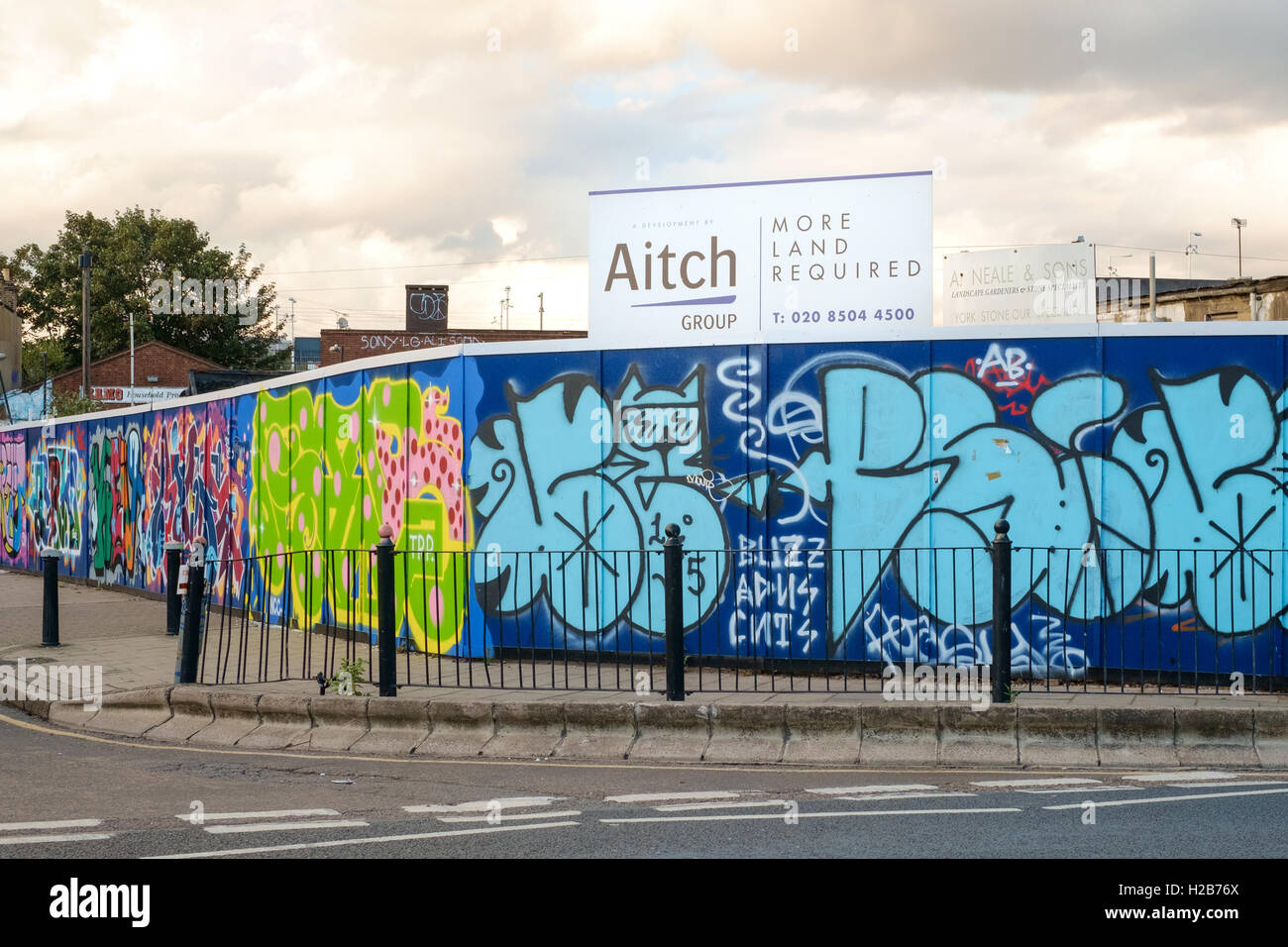 'More Land Required' sign above graffiti'd hoardings around a development site in Hackney Wick, East London Stock Photo