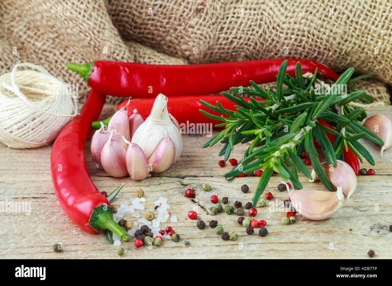 Condiments and spices - salt, rosemary, garlic, pink and black pepper, chilli. Selective focus. Rustic style Stock Photo