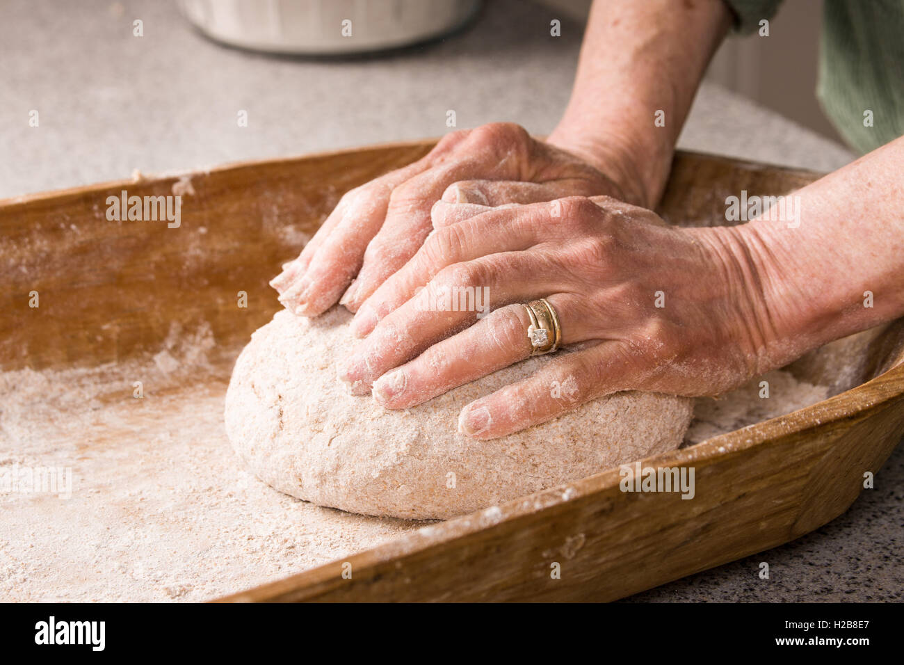 Woman kneading dough in a dough trough until it is smooth and elastic