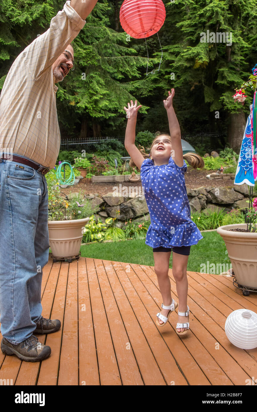 Three year old girl playing with a paper lantern with her grandfather in Issaquah, Washington, USA Stock Photo