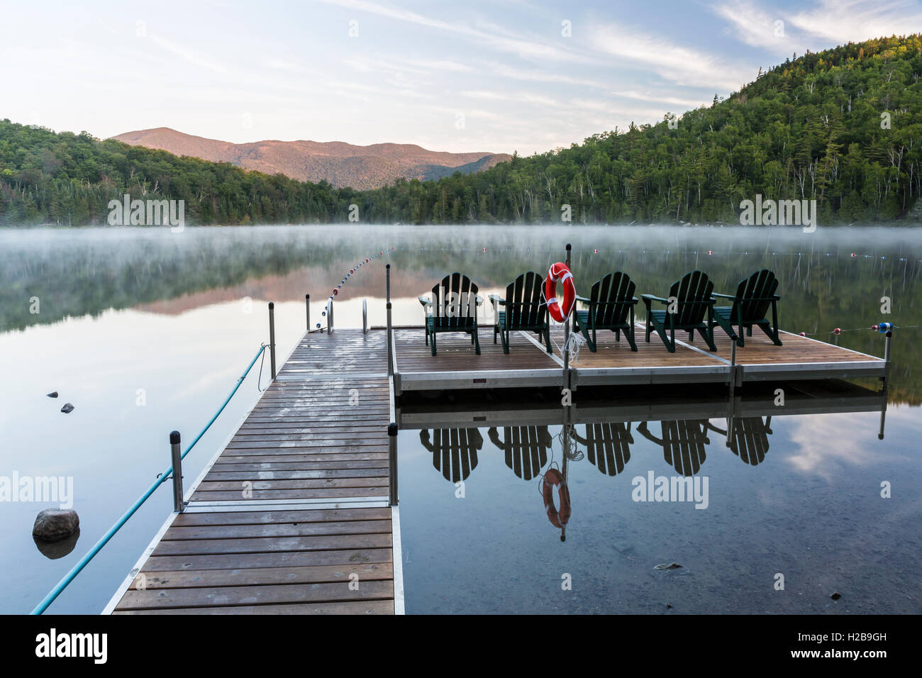 Adirondack Chairs on the Heart Lake dock on a misty morning in the High Peaks region of the Adirondacks near Lake Placid, NY Stock Photo