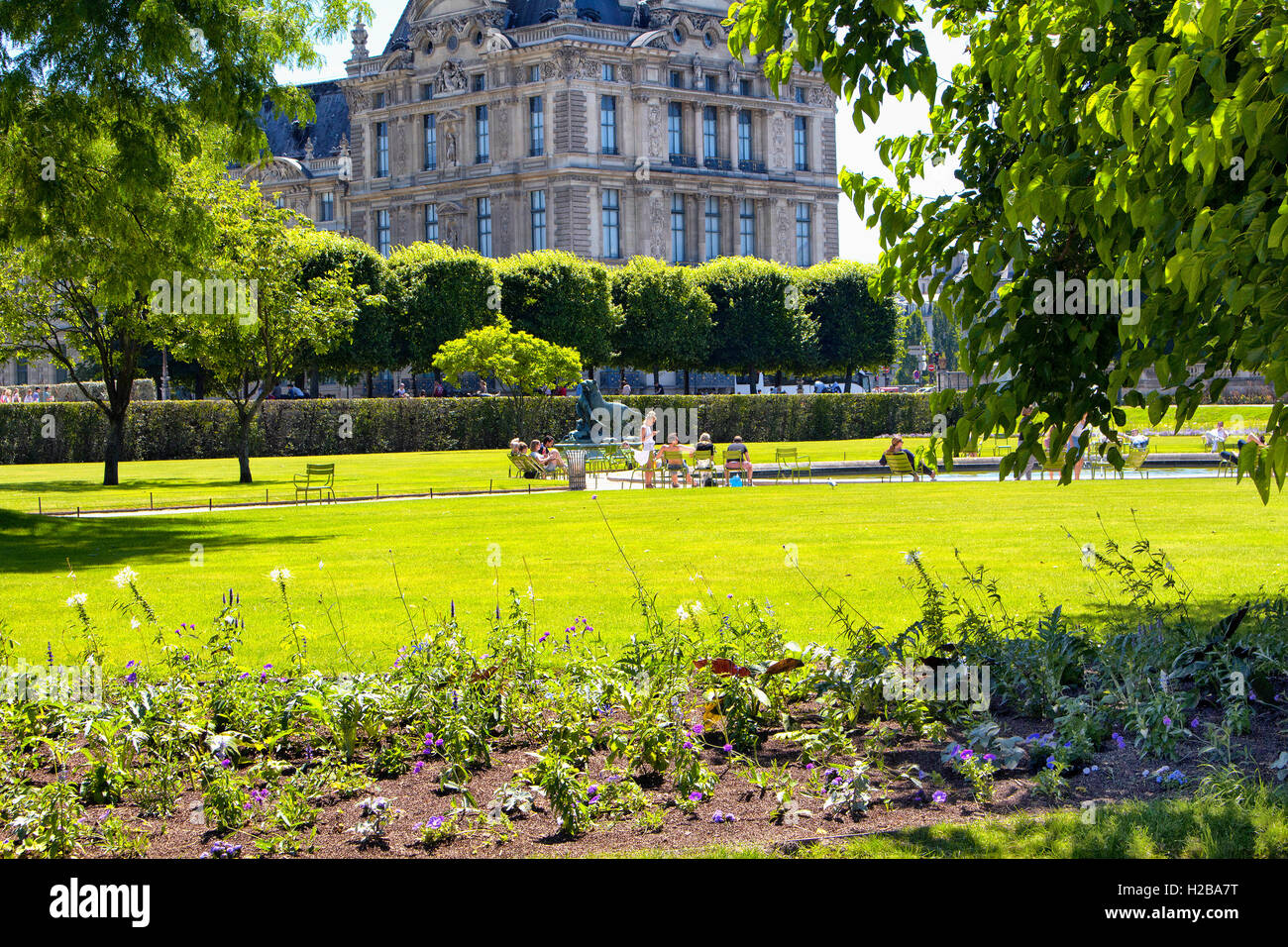 People hang out at Jardin des Tuileries in Paris. Statue and Orangerie Museum are also in the view. Stock Photo