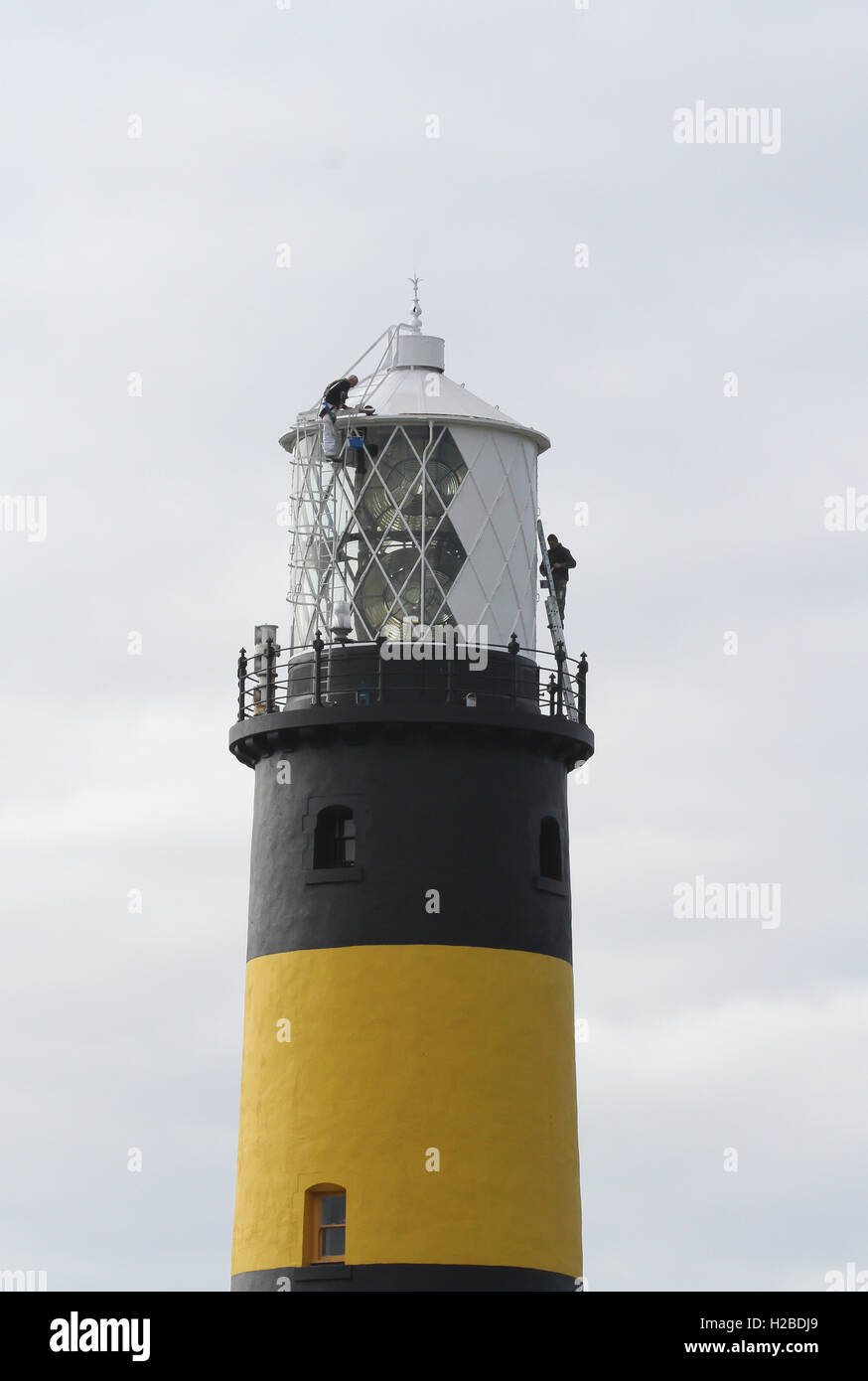 Industrial painters working at height in an unusual environment whilst painting a lighthouse at St John's Point County Down Northern Ireland. Stock Photo