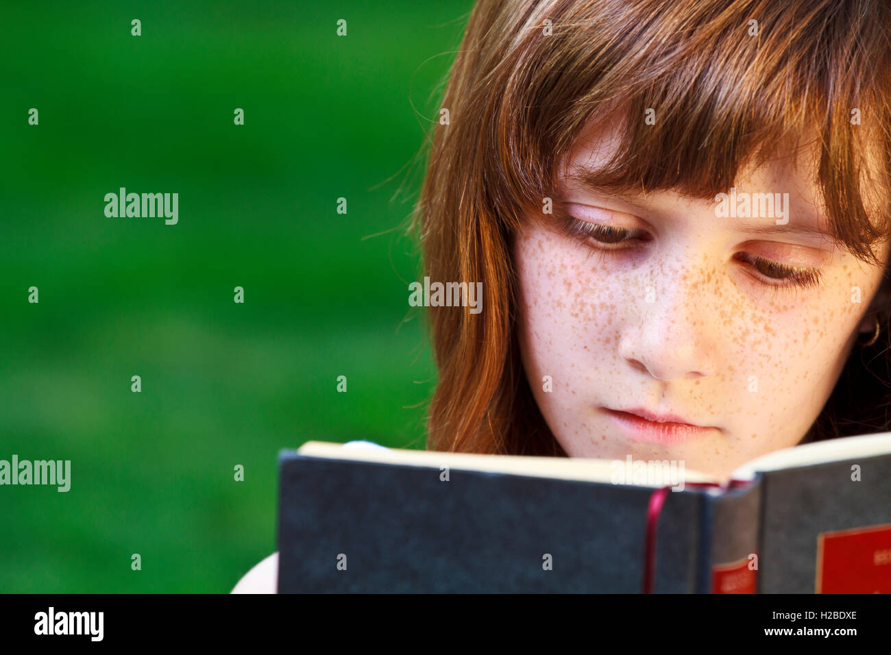 Young beautiful girl reading a book outdoor Stock Photo - Alamy