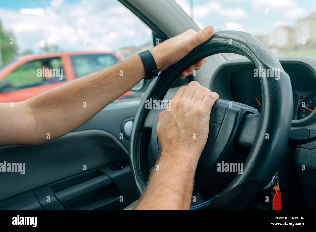 Nervous male driver pushing car horn in traffic rush hour, close up with selective focus on hand on the steering wheel Stock Photo