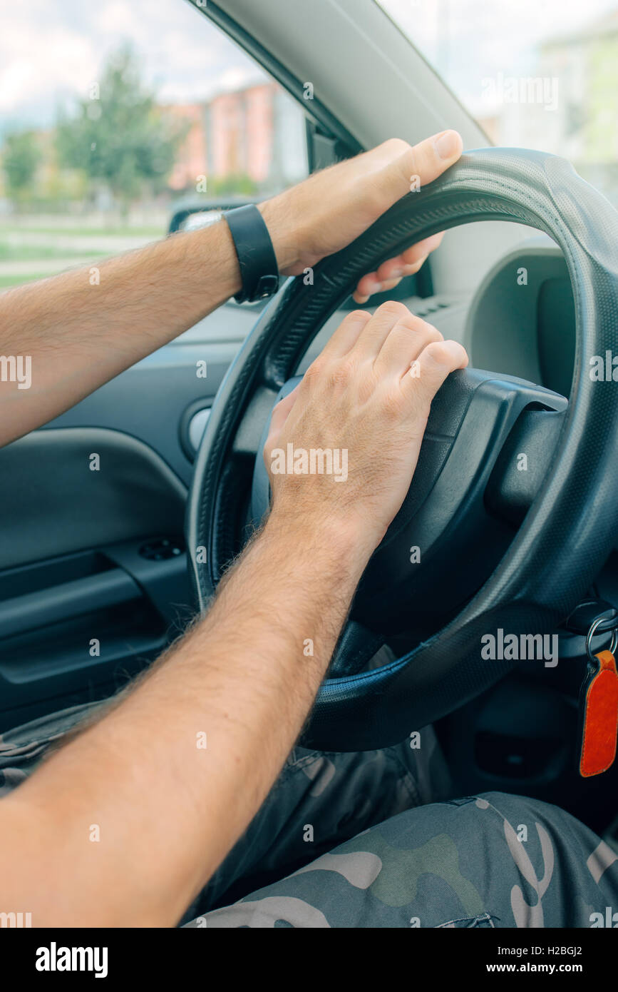 Nervous male driver pushing car horn in traffic rush hour, close up with selective focus on hand on the steering wheel Stock Photo
