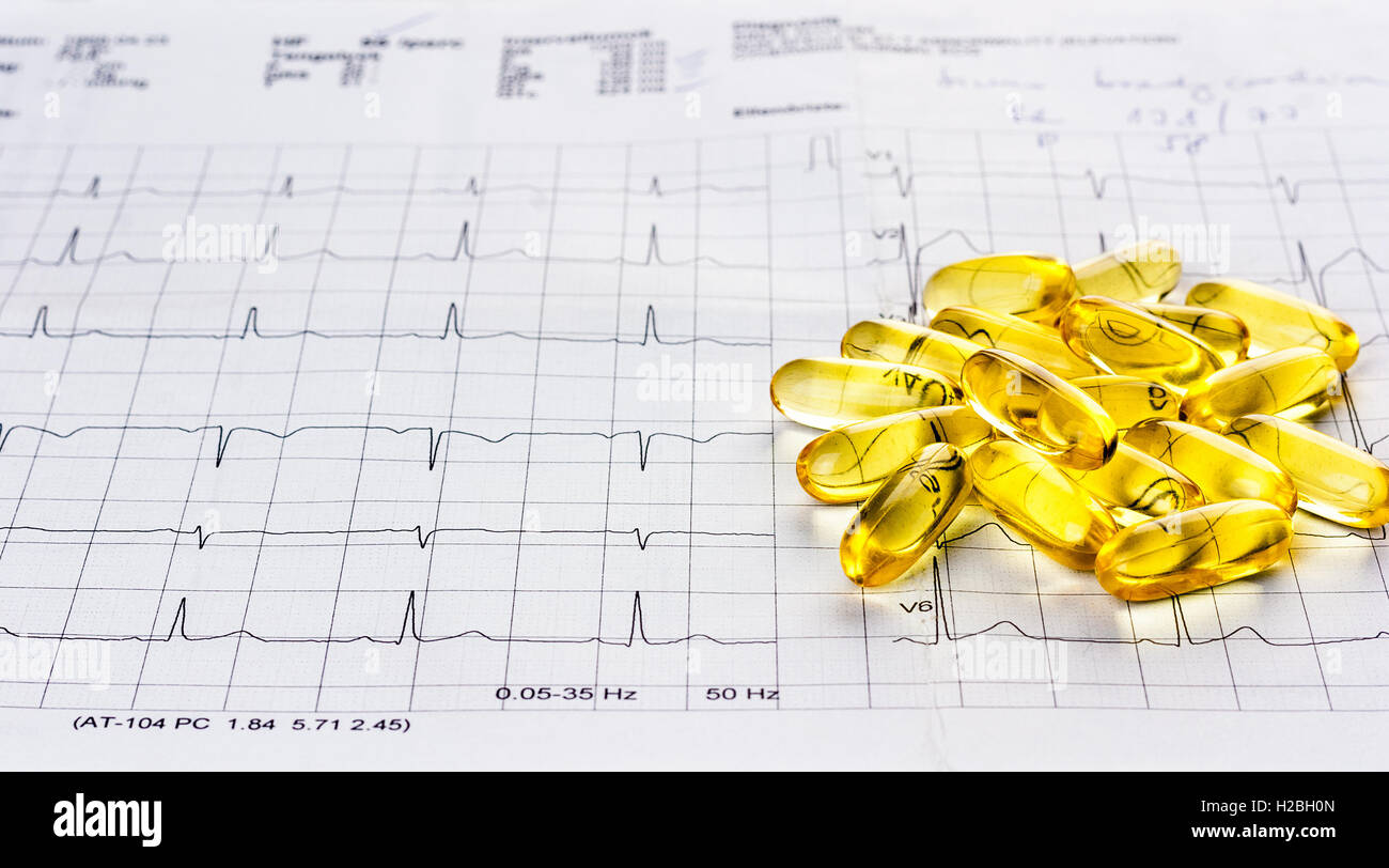 Omega 3 gel capsules on an ecg test result paper background Stock Photo