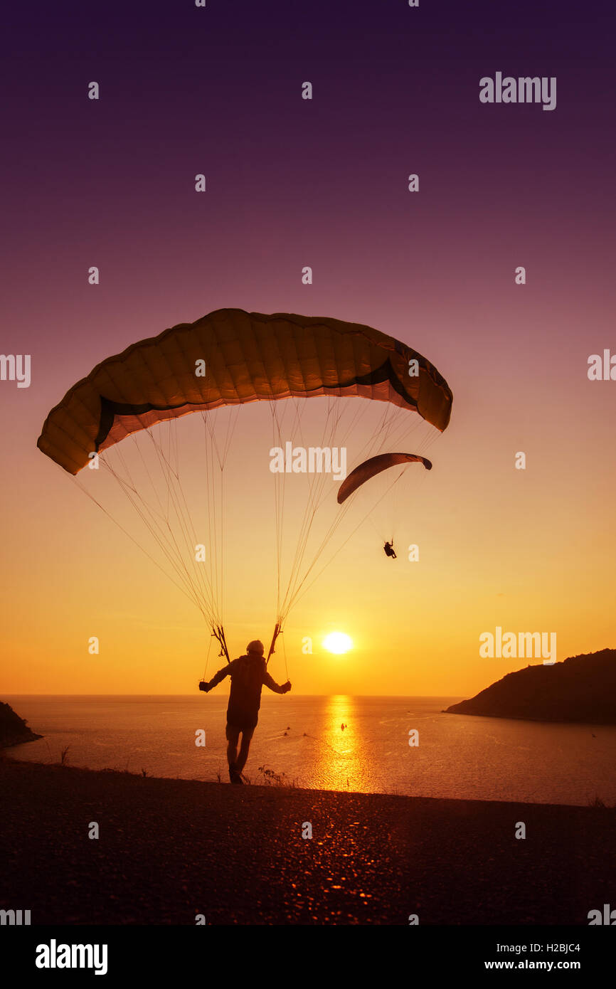Sskydivers ready to start flying on background of sunset sky and sea Stock Photo