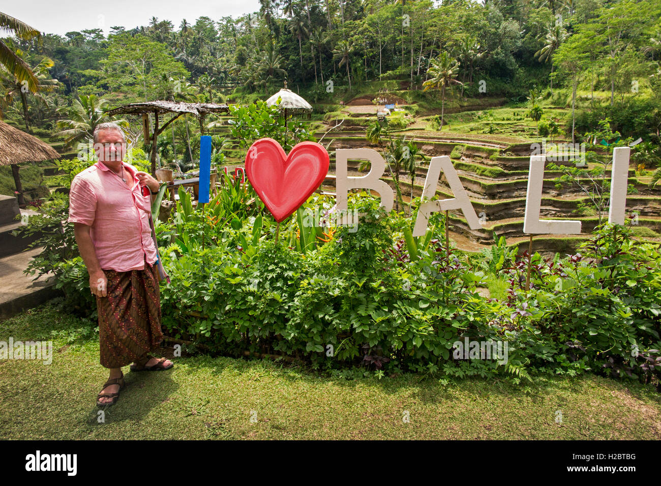 Indonesia, Bali, Tegallang, tourist wearing sarong at I love (heart) Bali sign in cafe garden Stock Photo