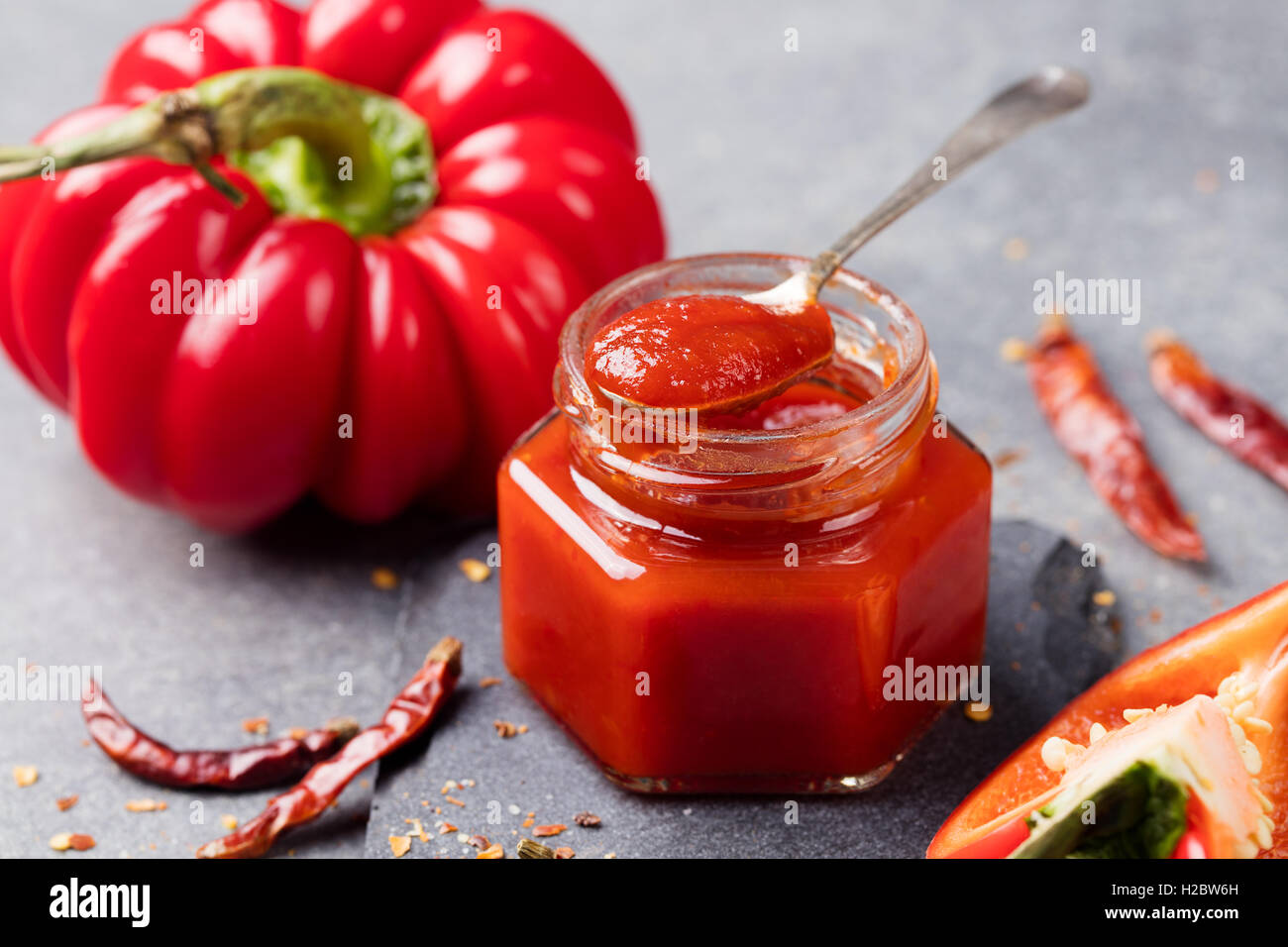 Tomato and chili sauce, jam, confiture in a glass jar on a grey stone