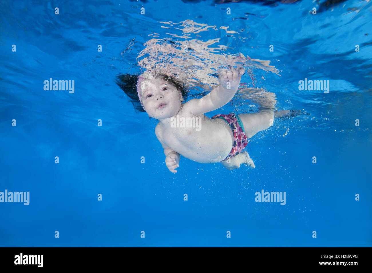 5 months infant girl learning to swim underwater in waterbaby class in
