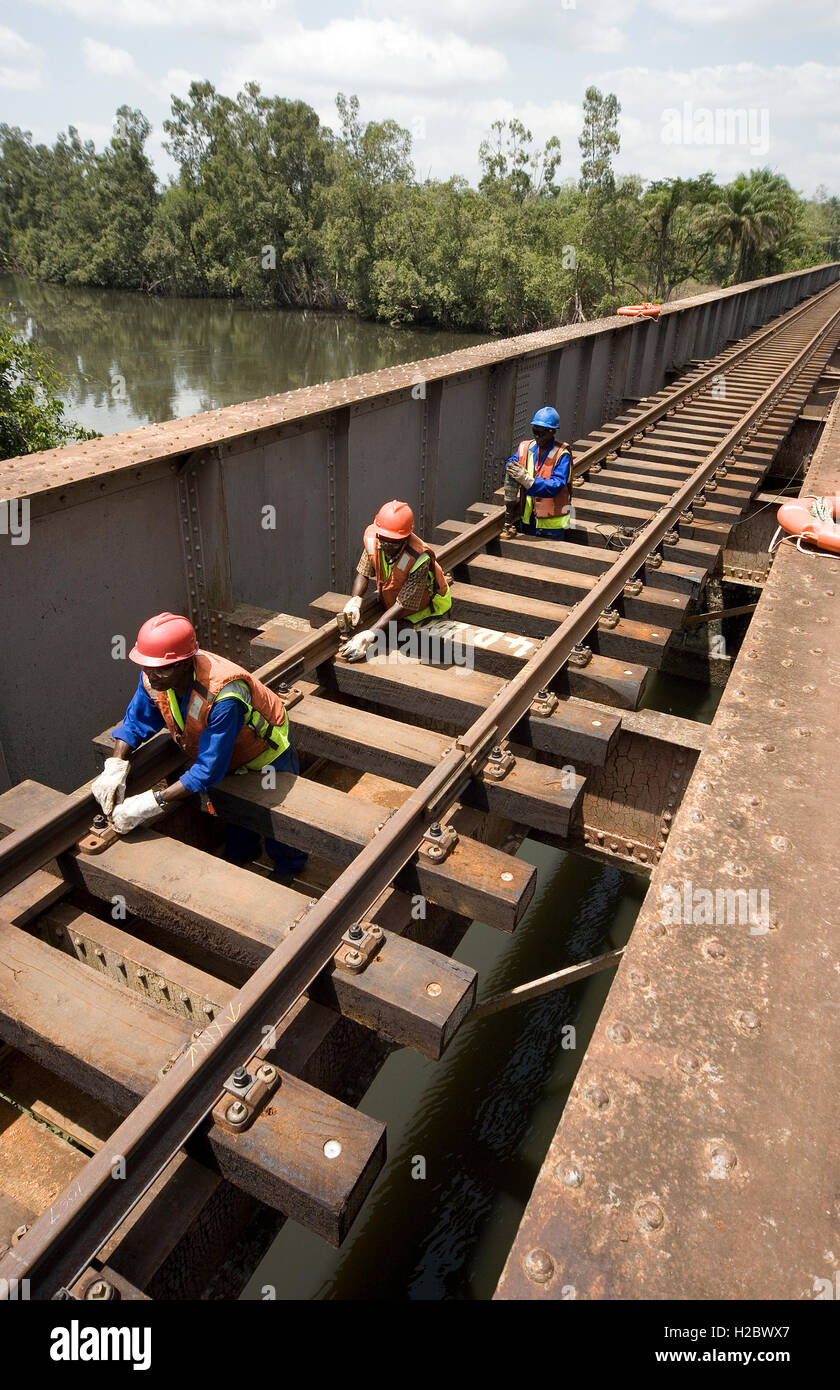 Railway track refurbishment, reinstatement and extension of rail line from port to iron ore mine. Bolting fixing plates to hold track to river bridge. Stock Photo