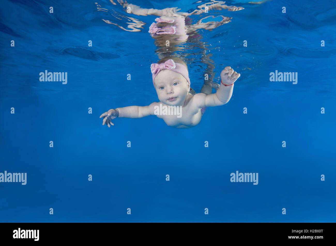 5 months infant girl learning to swim underwater in waterbaby class in