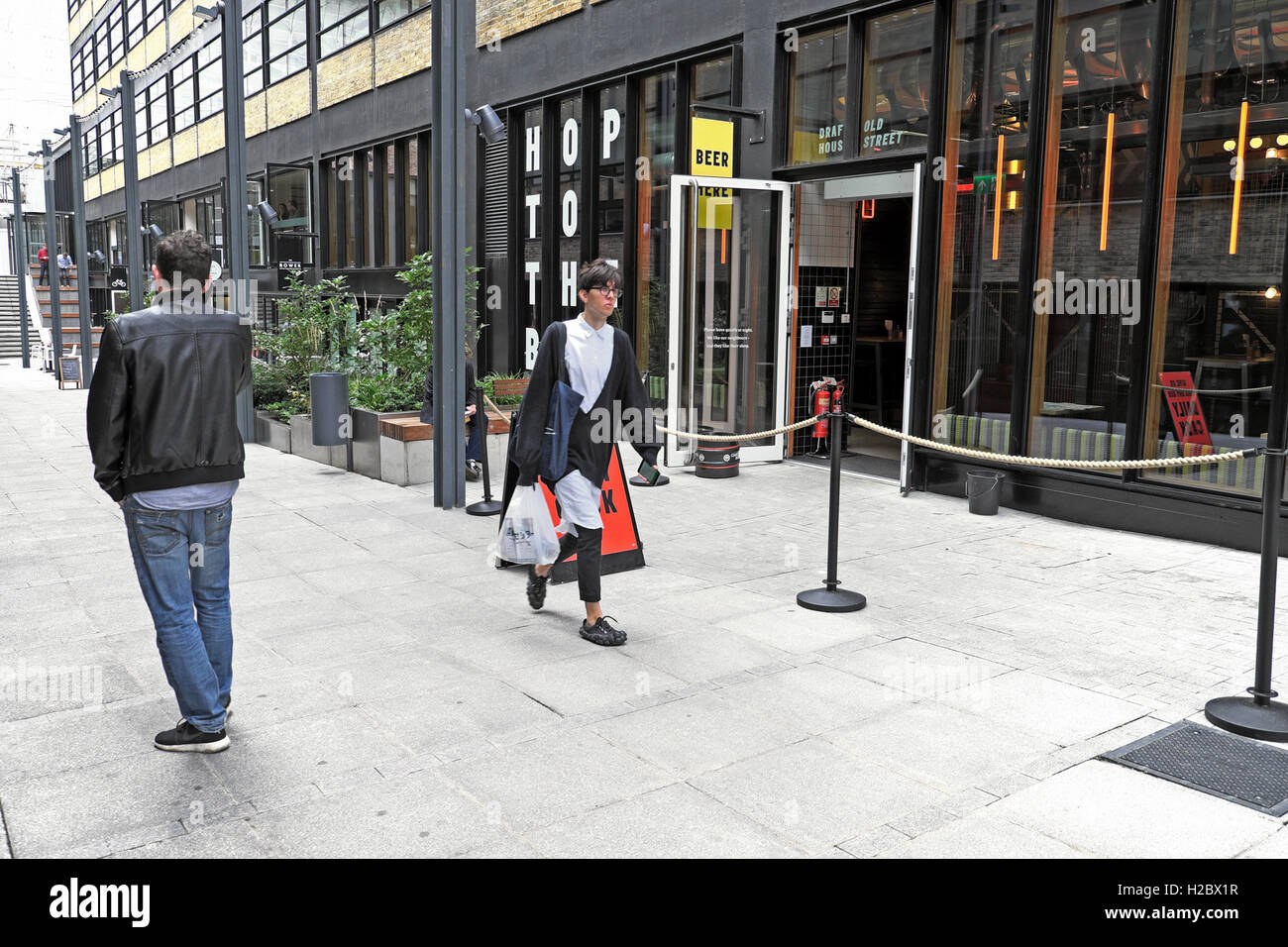 Trendy young person walking past The Draft House craft beer pub at the Bower complex  Old Street, East London EC1V UK   KATHY DEWITT Stock Photo