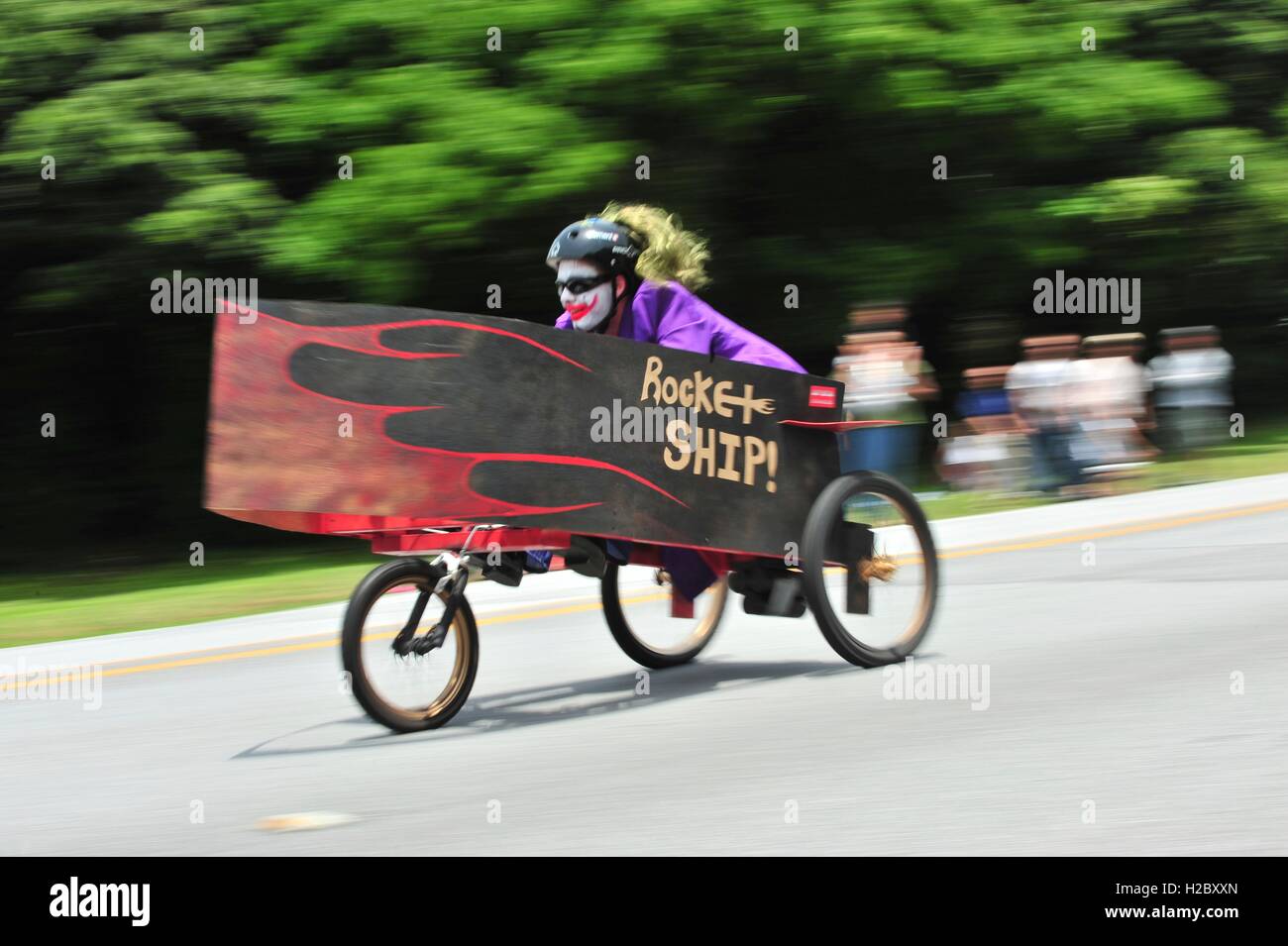 A woman in Joker facepaint rides her homemade soapbox derby race car painted 'Rocket Ship' down a hill on Douglas Boulevard during the American Red Cross Derby Day May 1, 2010 at the Kadena Air Base in Okinawa City, Okinawa, Japan. Stock Photo
