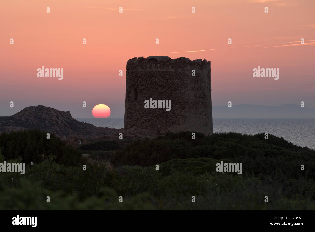 La Torre Spagnola, the Spanish Tower, in Isola Rossa Sardinia with the sun setting behind, September Stock Photo
