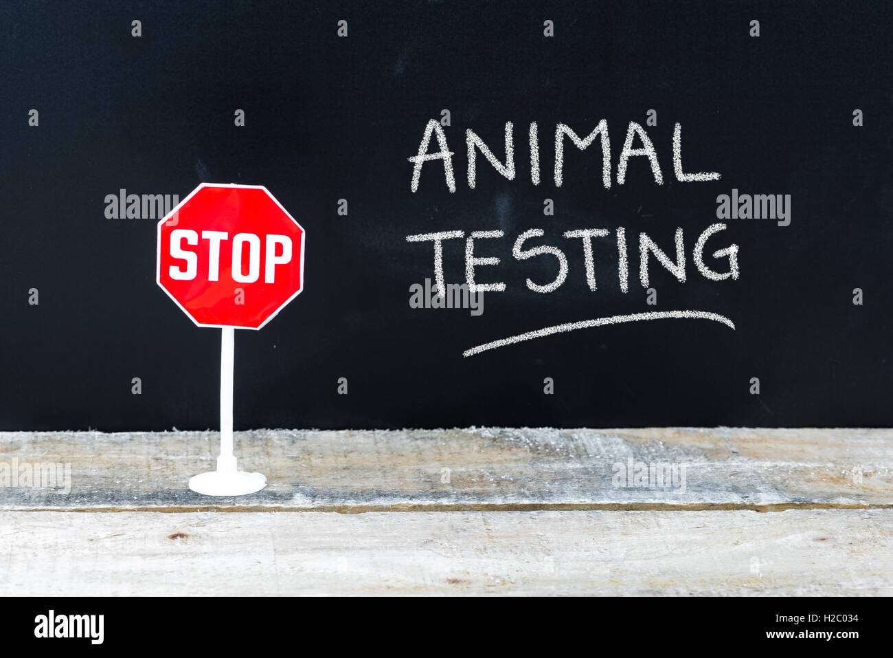 Mini STOP sign over chalkboard background and table, STOP ANIMAL ...