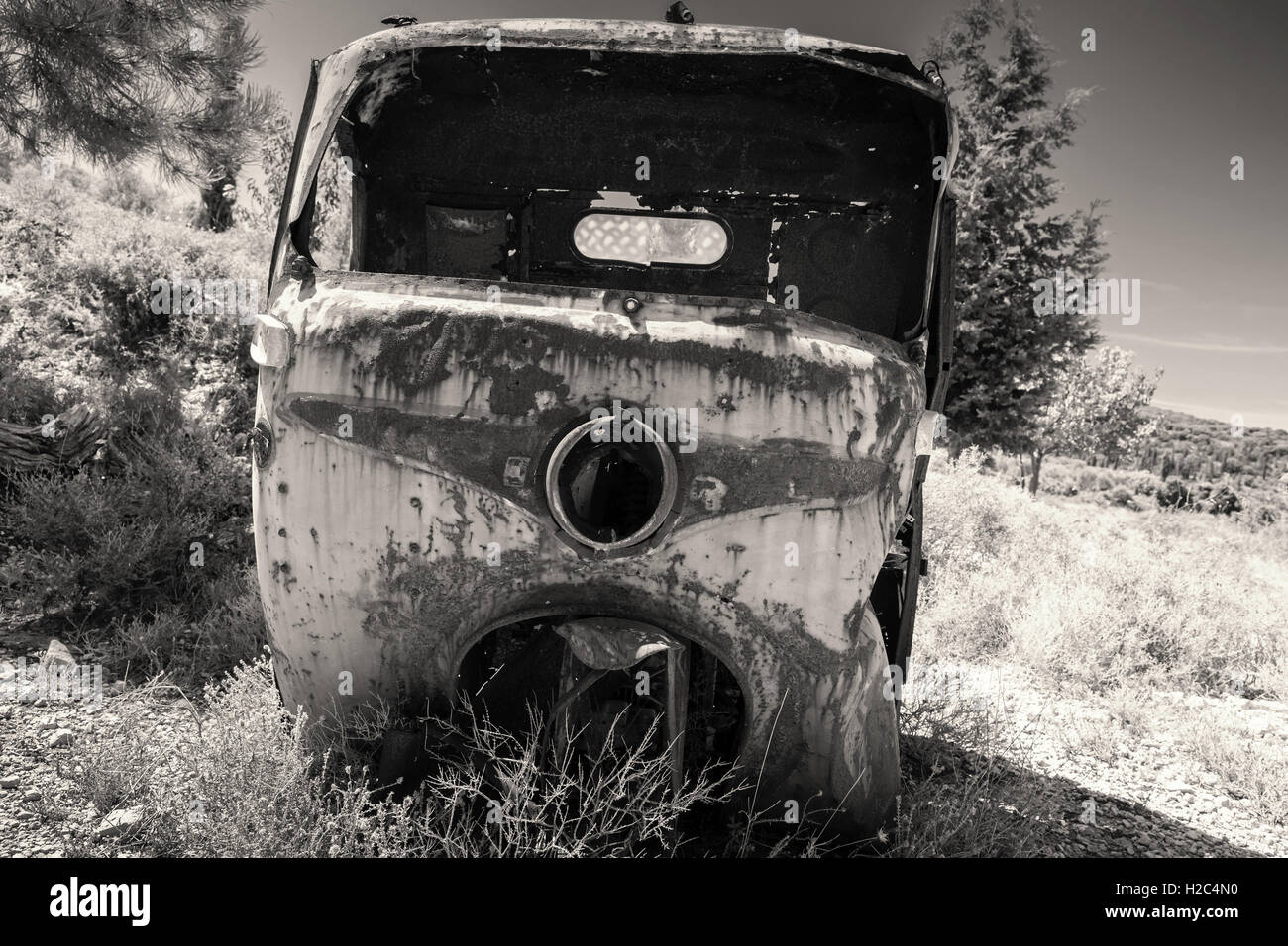 Abandoned rusted body of three-wheeled light commercial vehicle, old style filter effect, monochrome retro photo Stock Photo
