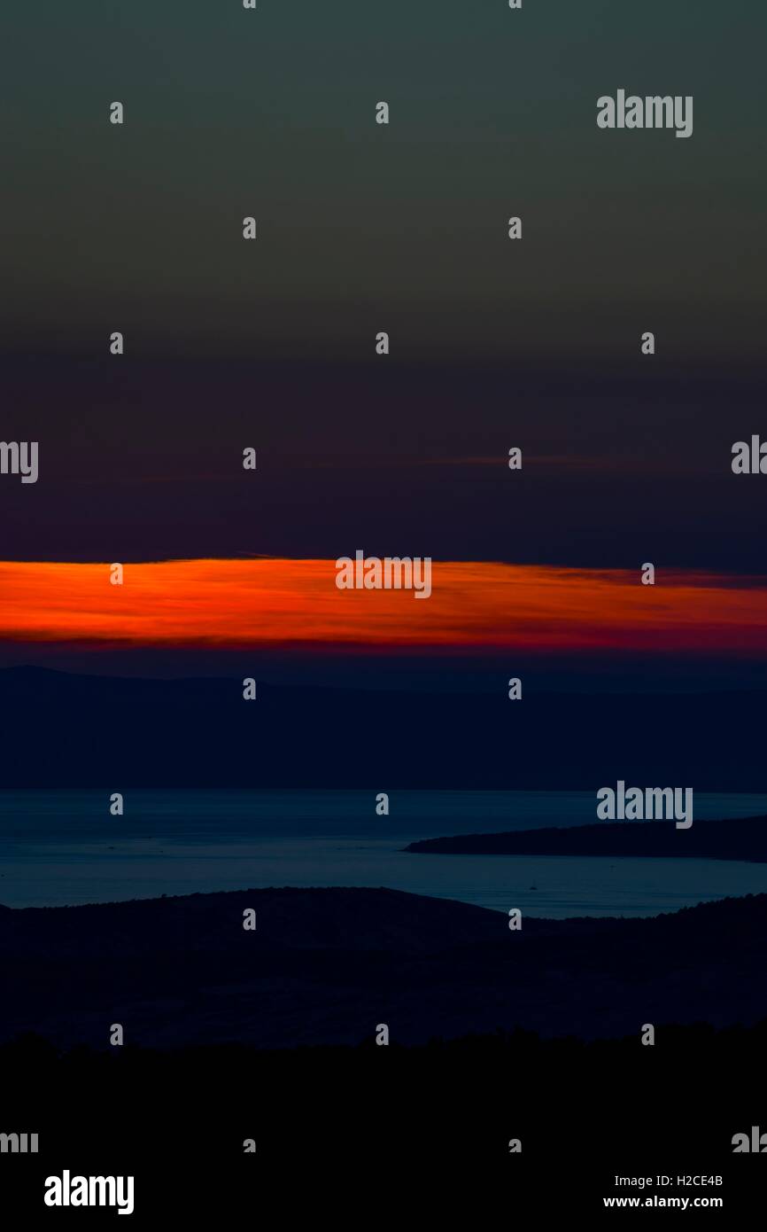 Vertical seascape narrow Red stripe of Red sunset dusk light between clouds seaside coastline landscape Stock Photo