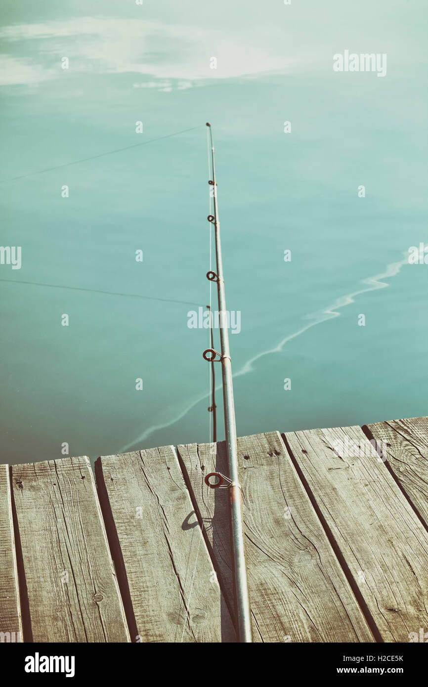 Retro toned fishing rod on a wooden pier. Stock Photo