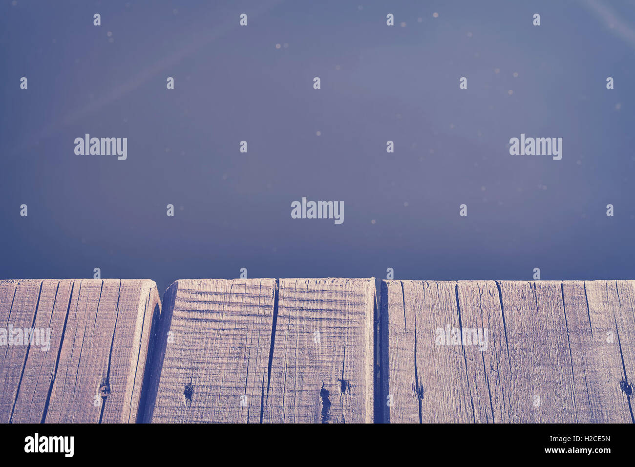 Vintage toned close up photo of an old wooden pier by a lake, background with space for text. Stock Photo