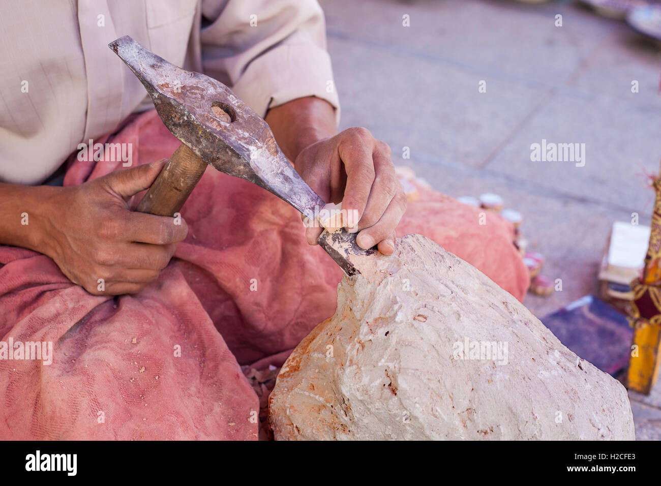 Artisan makes pieces for mosaic craftwork. He is shaping pieces from glazed tiles Stock Photo