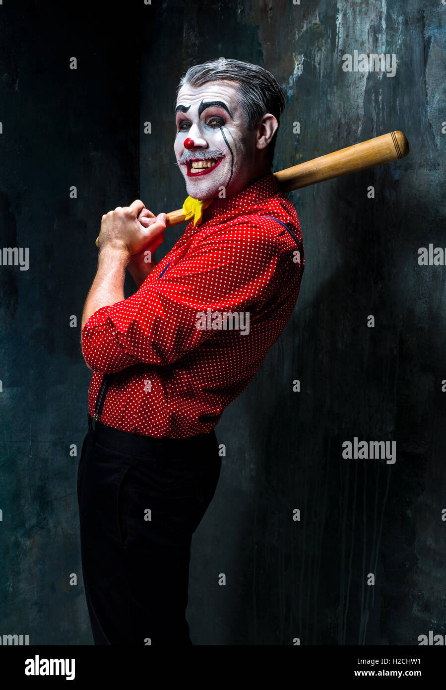 The scary clown and baseball-bat on dack background. Halloween concept Stock Photo