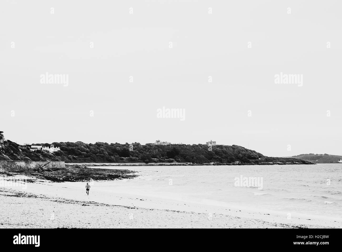 High contrast photograph of wild swimmer emerging from the sea at Gylyngvase Beach, Falmouth, Cornwall Stock Photo