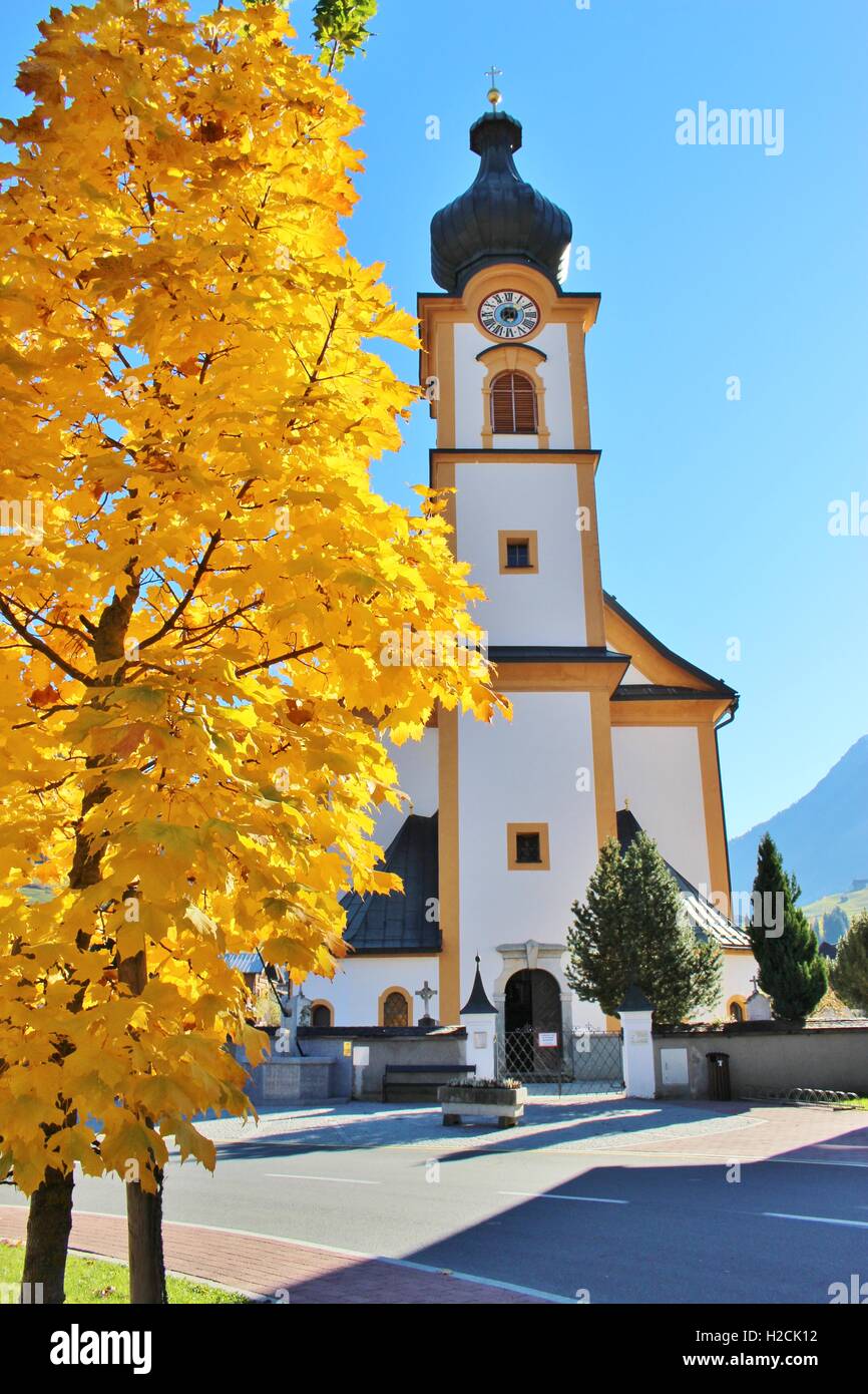 Autumn in Austria: Tree with very yellow autumn leafs and the baroque parish church or Pfarrkirche of Mittersill, Salzburg Land. Stock Photo