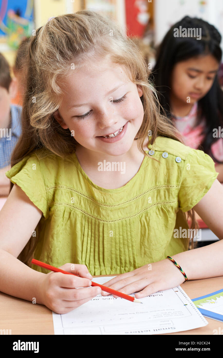 Female Elementary School Pupil Working At Desk Stock Photo