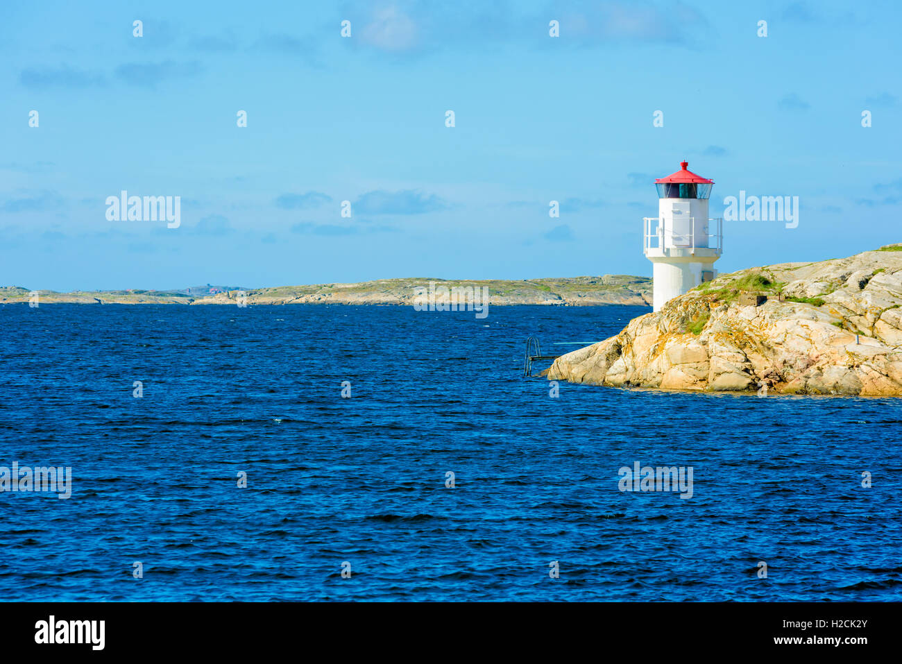 Small white and red lighthouse on cliff in barren Swedish west coast archipelago. Stock Photo