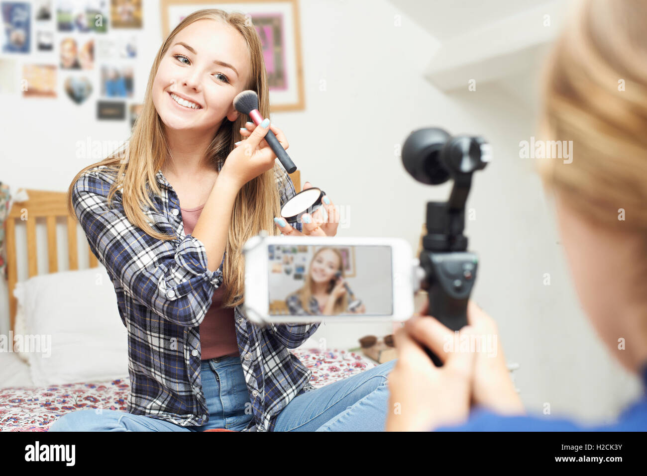 Two Teenage Girls Recording Beauty Blog In Bedroom Stock Photo