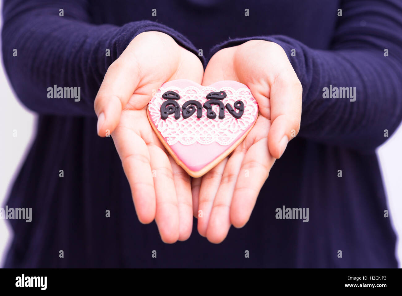 hands holding cookie with thai text mean 'missing you'. Stock Photo