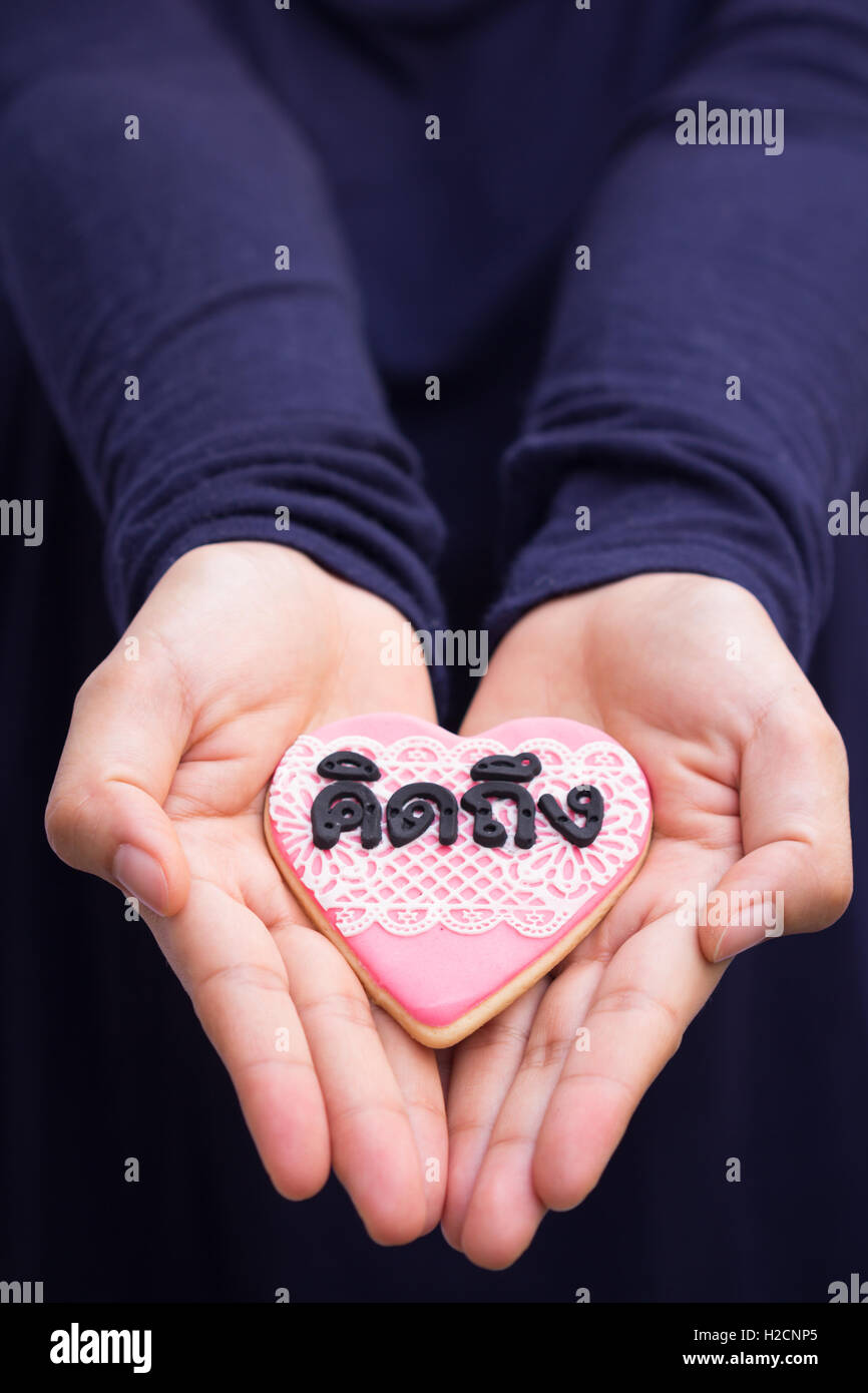 hands holding cookie with thai text mean 'missing you'. Stock Photo