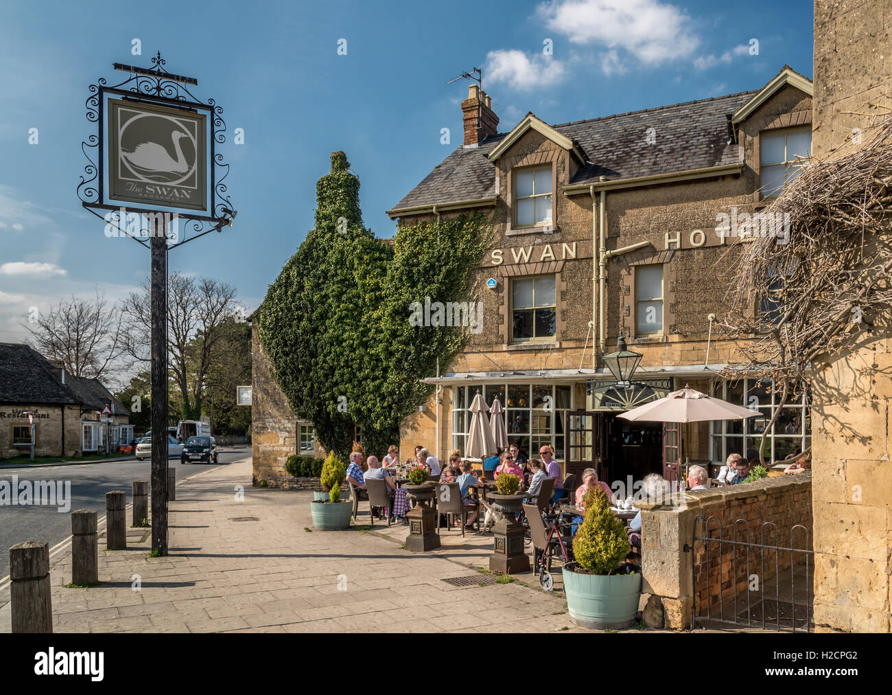 People enjoying an early evening drink in the sunshine in front of a typical village pub in the Cotswolds. Stock Photo