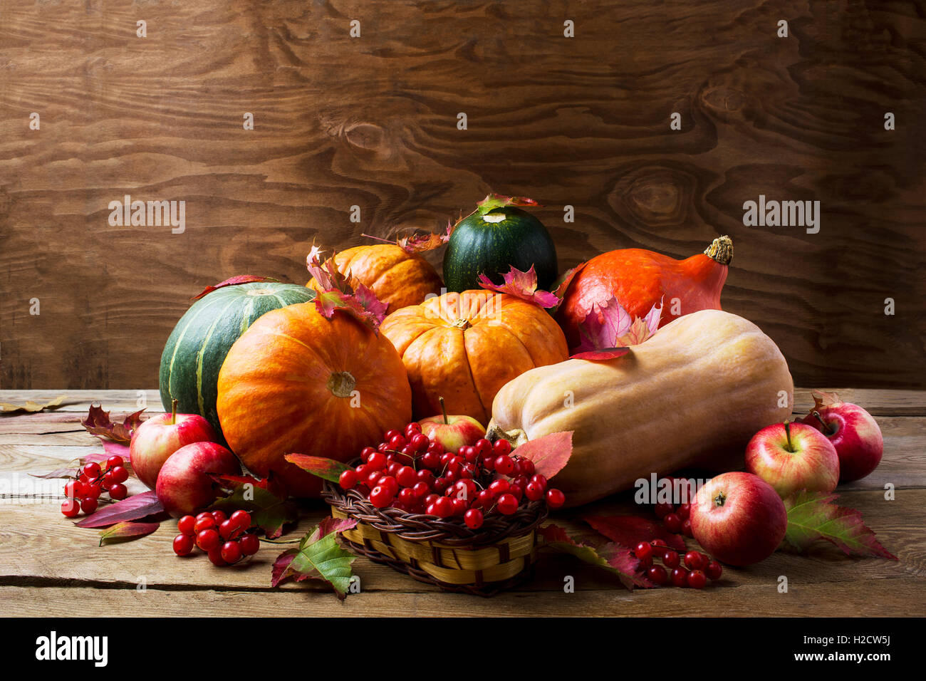 Abundant harvest concept with pumpkins, apples, berries and fall leaves. Thanksgiving background with pumpkins and seasonal berr Stock Photo