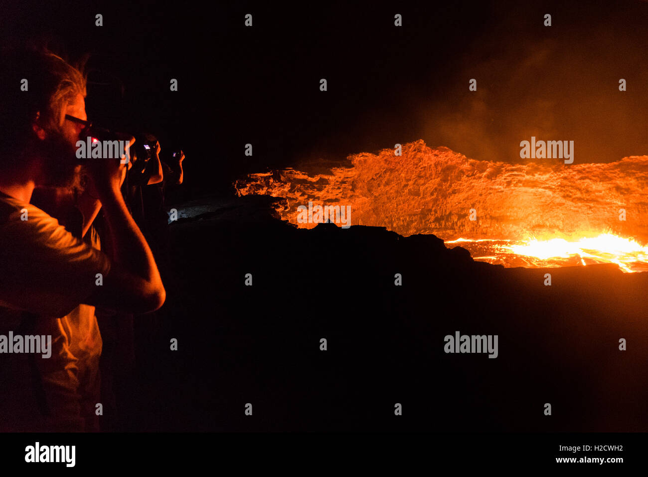 tourists take photos at Erta Ale crater rim - an active shield volcano in Ethiopia Stock Photo