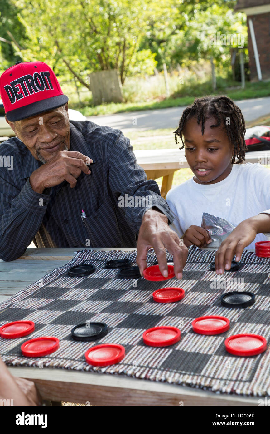 Detroit, Michigan - An elderly man and a young boy team up to play checkers at a block party. Stock Photo