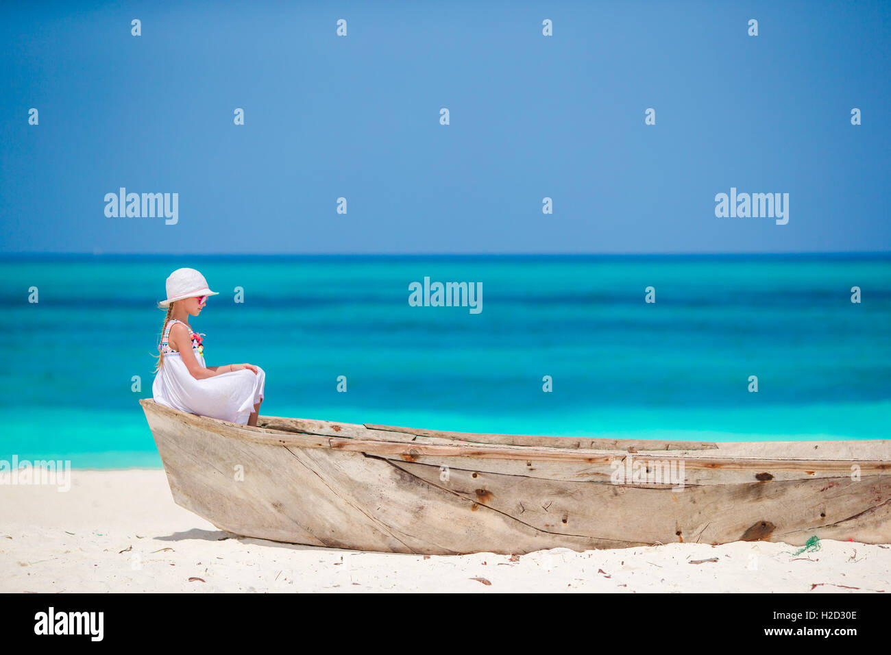 Adorable little girl in white dress at beach during summer vacation