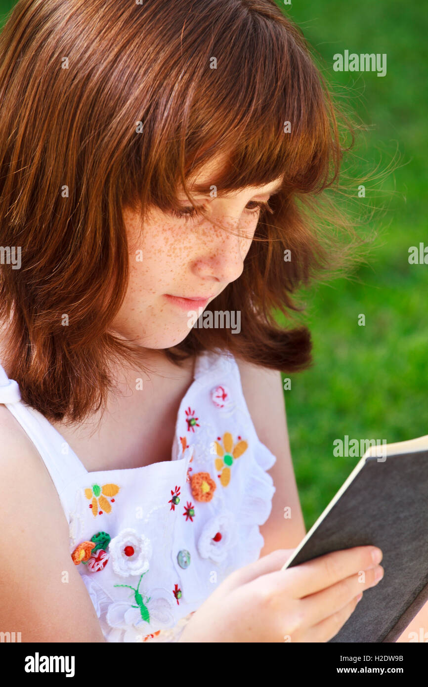 Young beautiful girl reading a book outdoor Stock Photo - Alamy