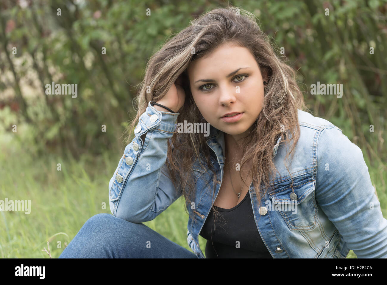 Portrait of fine teenage girl sitting outdoors. Girl is looking at the