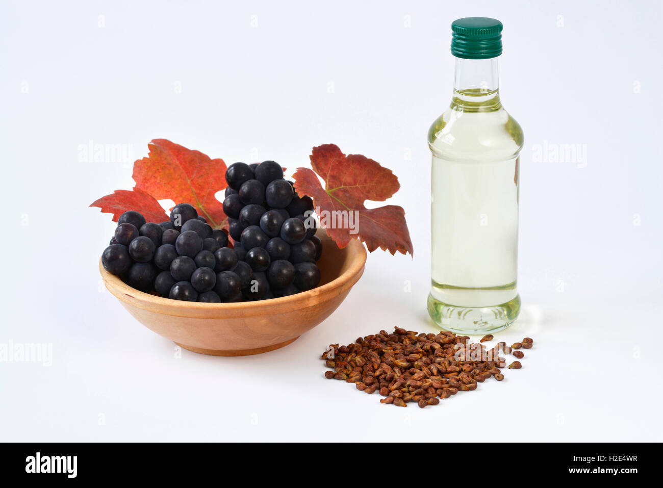 Grape Vine (Vitis vinifera). Leaves, grapes, seeds and a bottle with grape seed oil. Studio picture against a white background. Germany Stock Photo