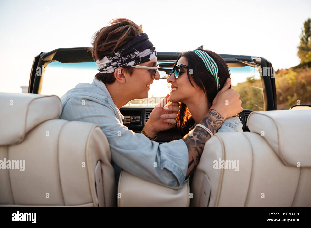 Happy young couple kissing in cabriolet in summer Stock Photo