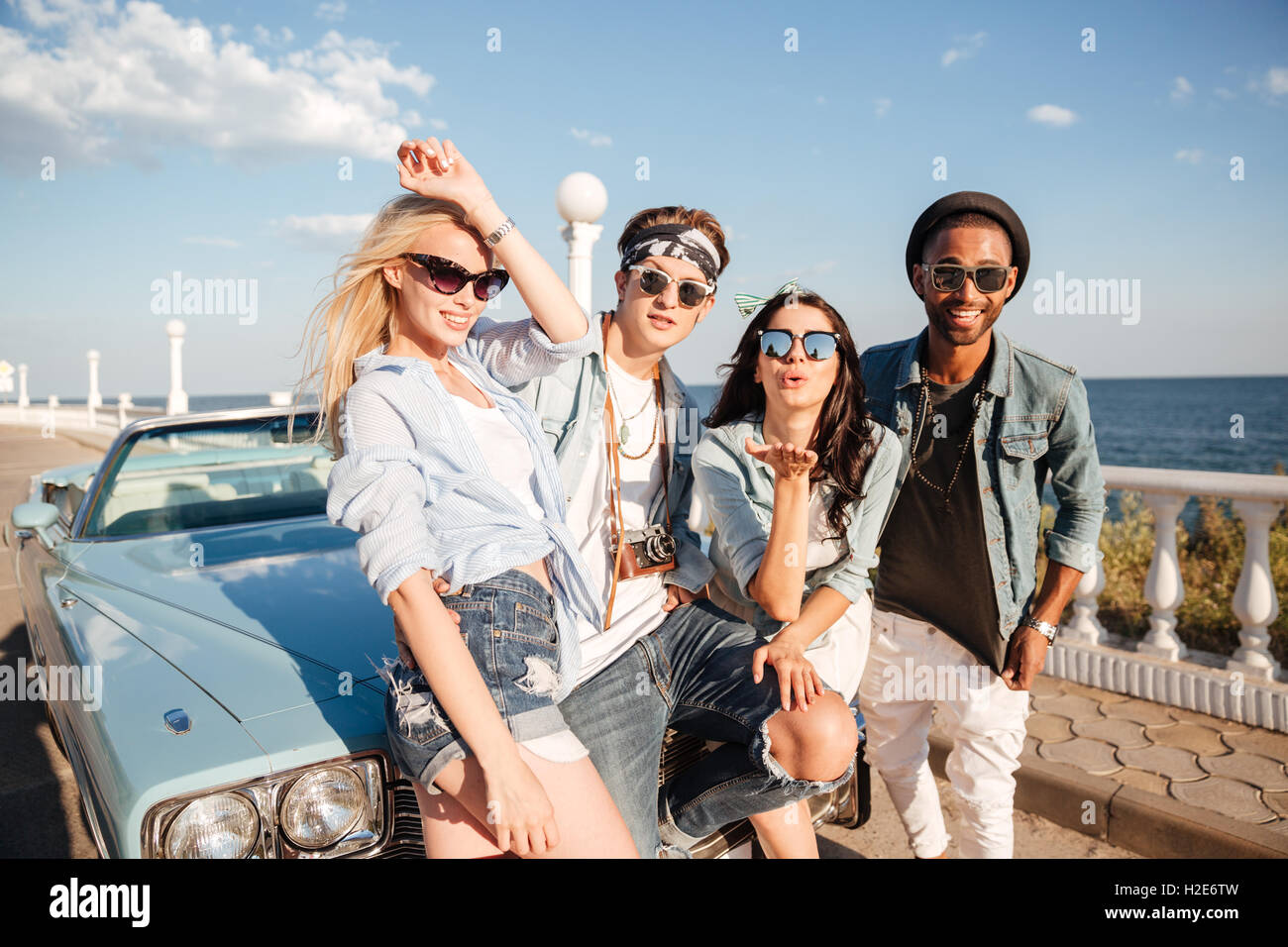 Group of smiling young friends standing outdoors in summer together Stock Photo