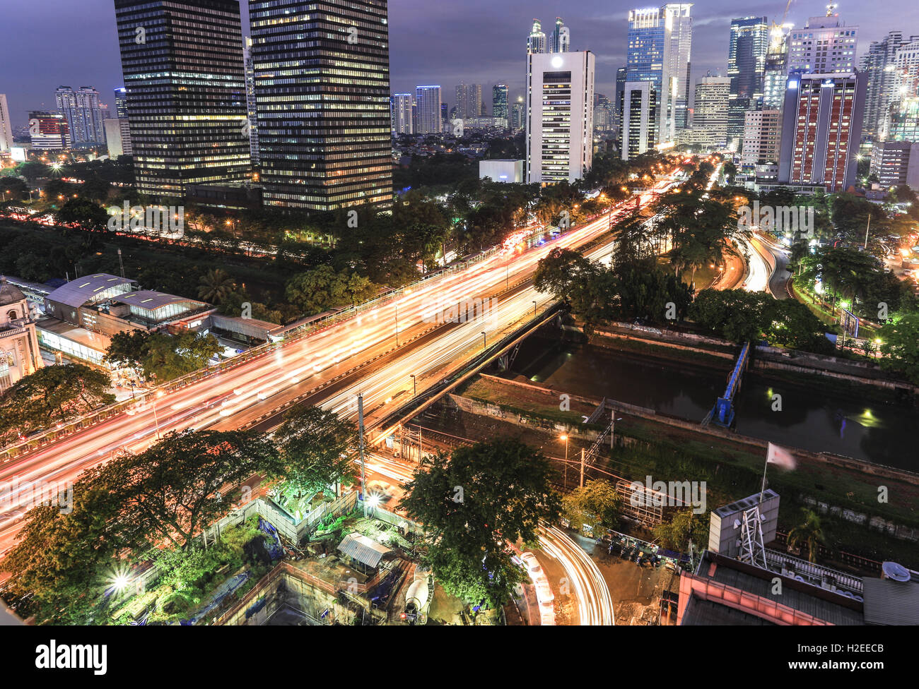 Traffic, captured with blurred motion, rush through Jalan Sudirman, the main avenue in the business district at night in Jakarta Stock Photo