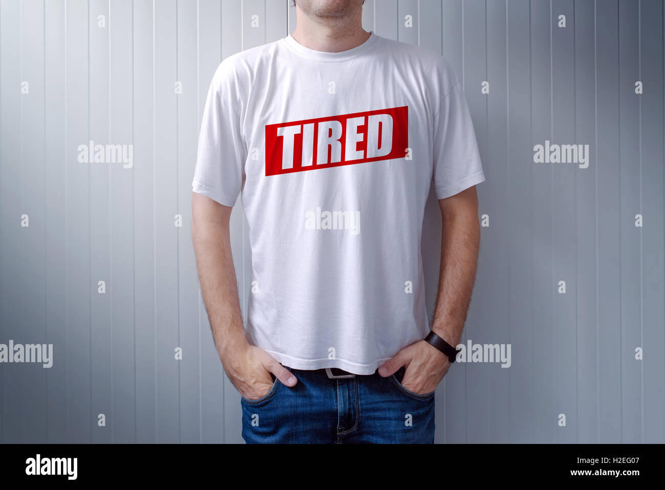 Guy wearing white t-shirt with label Tired printed on chest, text is added in post production Stock Photo